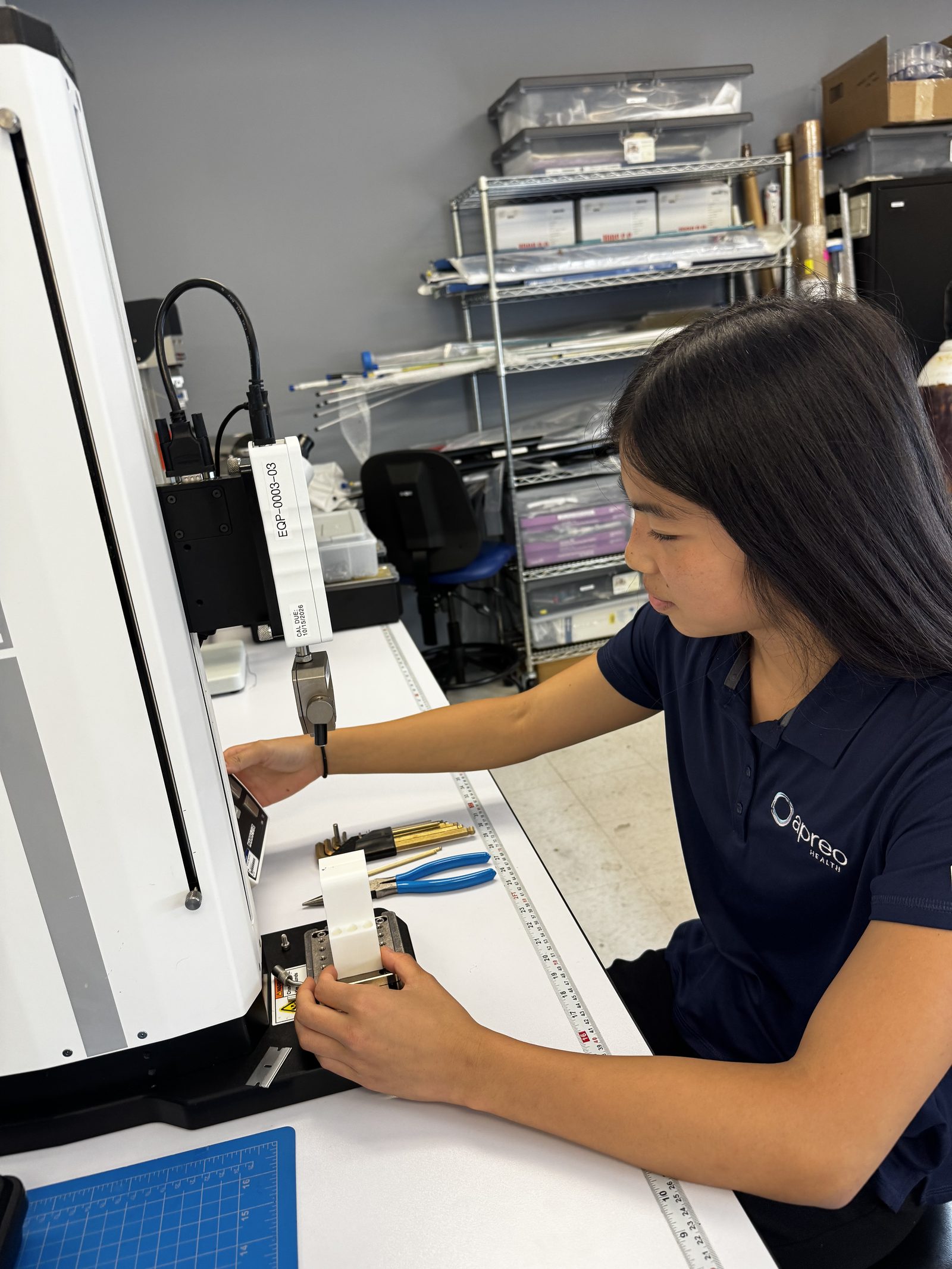 Kristin Der operating a tensile-test machine at Apreo Health